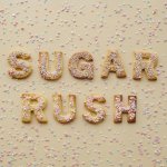 Top view of alphabet-shaped sugar cookies with colorful sprinkles spelling 'SUGAR RUSH'.